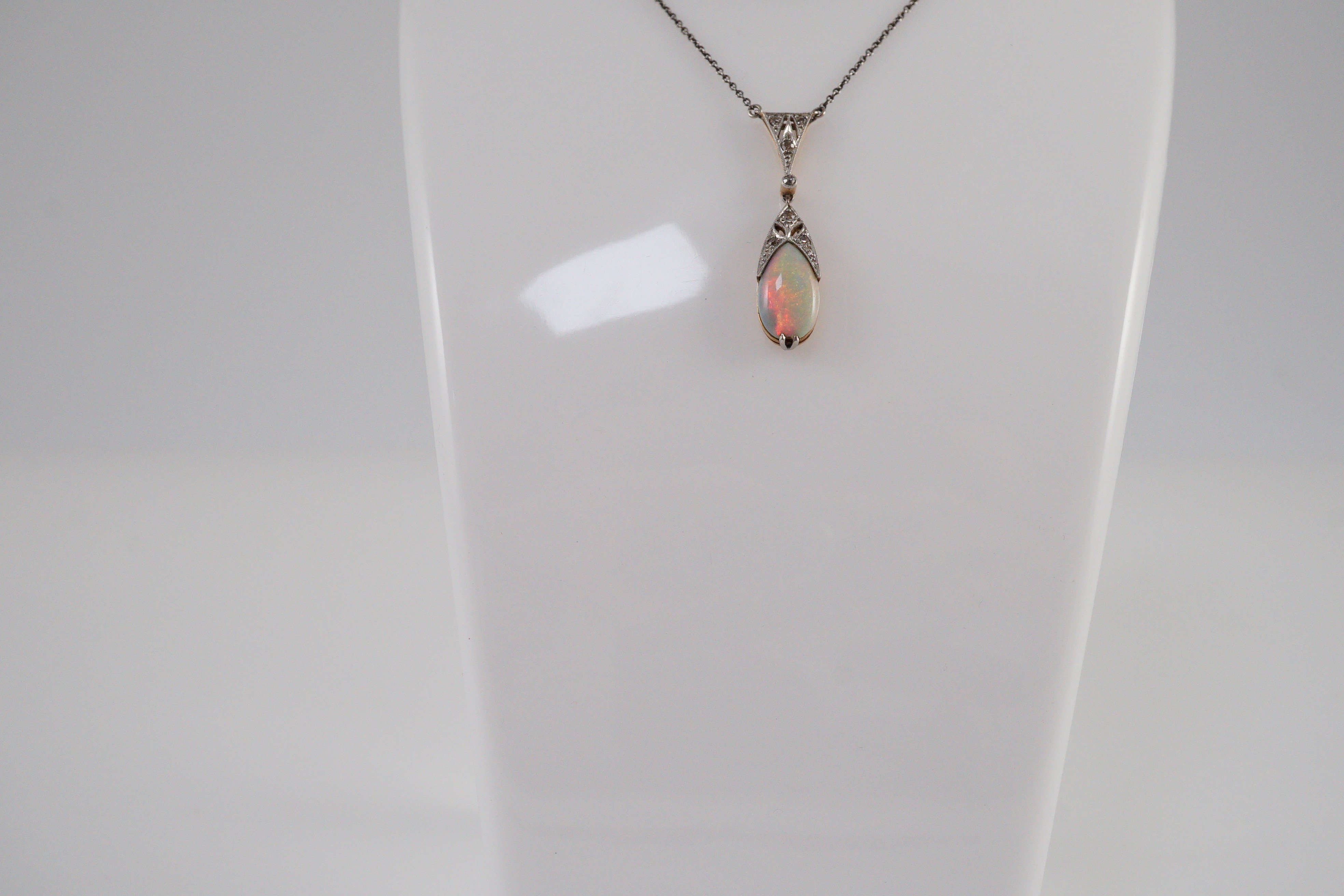 A 1920's gold and platinum, white opal and millegrain set diamond cluster pear shaped drop pendant necklace